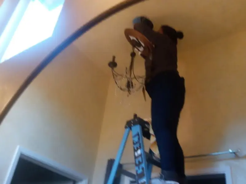 Electrician installing a chandelier in a Putnam residence
